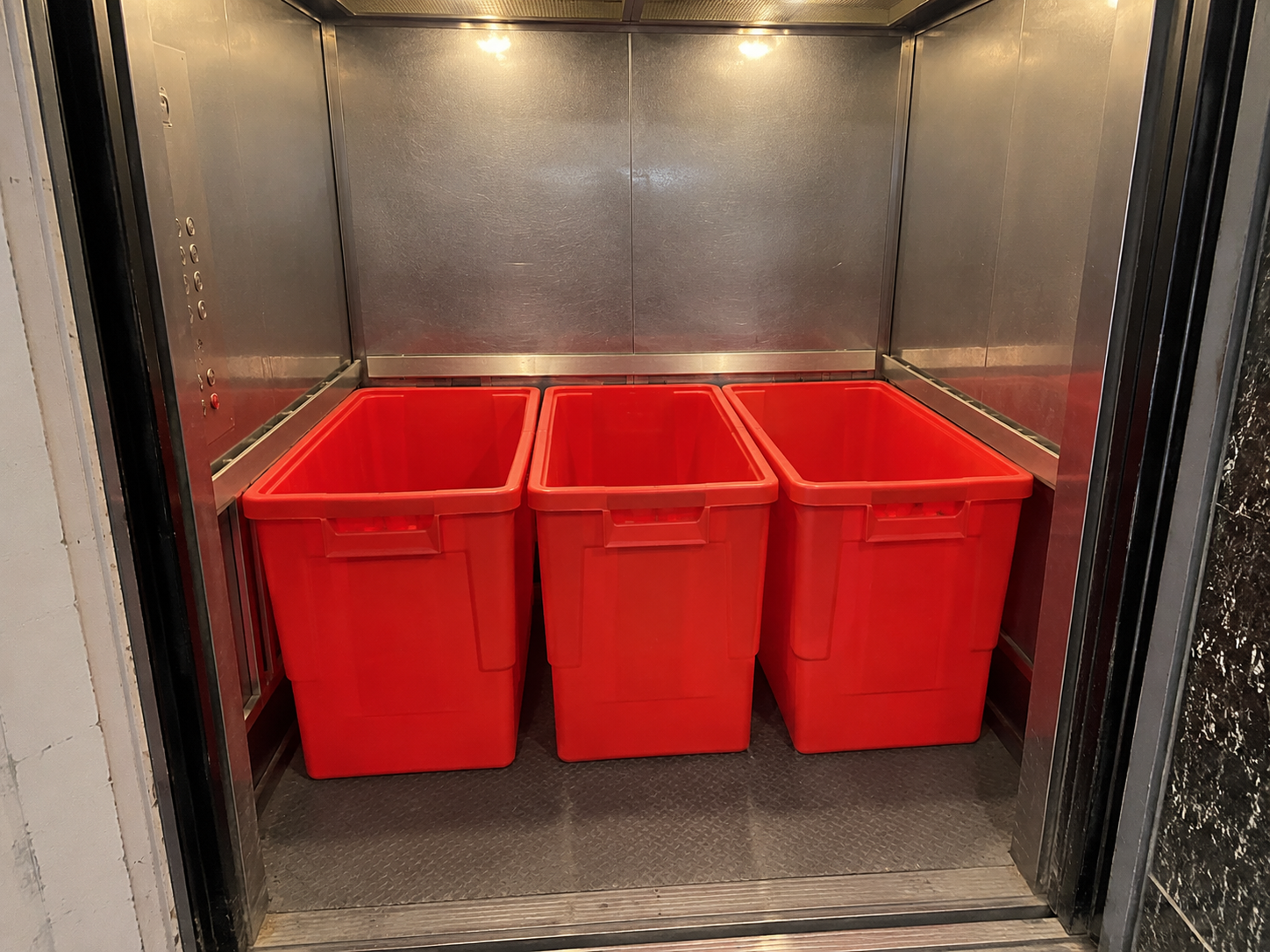Three EazyCrate plastic moving bins loaded inside narrow pre-war apartment service elevator