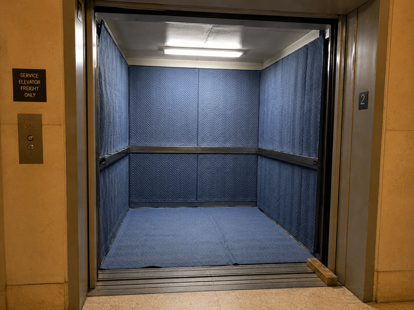 NYC apartment building service elevator with moving blanket pads installed — the standard setup for a freight elevator reservation